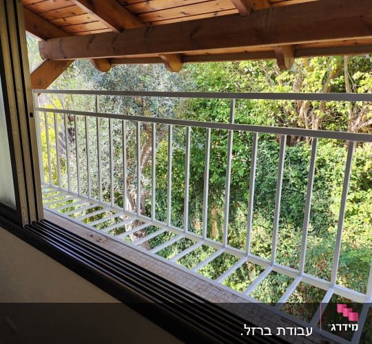 מרפסת עם מעקה מתכת לבן וחלון פתוח